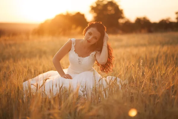 Feliz bela noiva jovem lá fora em um prado de verão no pôr do sol — Fotografia de Stock