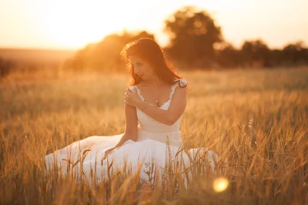 Feliz bela noiva jovem lá fora em um prado de verão no pôr do sol — Fotografia de Stock