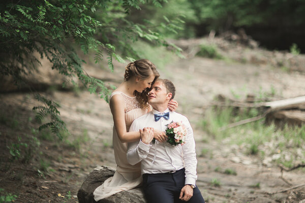 Elegant gentle stylishElegant gentle stylish groom and bride near river with stones. Wedding couple in love.