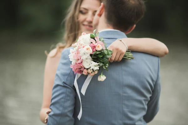 Beautiful wedding couple, bride,groom kissing and posing on the bridge near lake — Stock Photo, Image