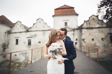 Güzel, romantik bir düğün. Yeni evliler. Eski kalenin yakınlarında sarılıyorlar.