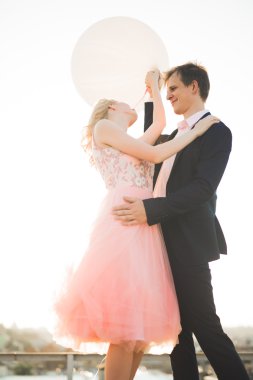 Çatıda mükemmel şehir manzaralı elele ve sarılma poz aşık genç bir çift. Güzel gün batımı