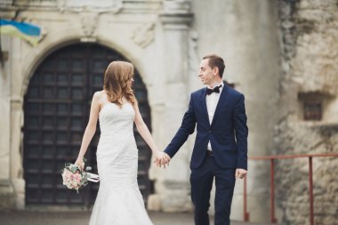 Güzel, romantik bir düğün. Yeni evliler. Eski kalenin yakınlarında sarılıyorlar.