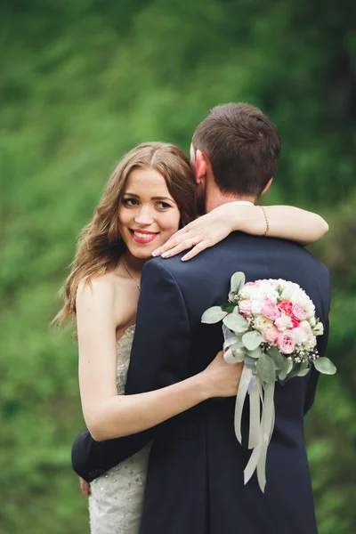 Feliz boda pareja abrazándose y sonriendo el uno al otro en el fondo hermosas plantas en el castillo — Foto de Stock