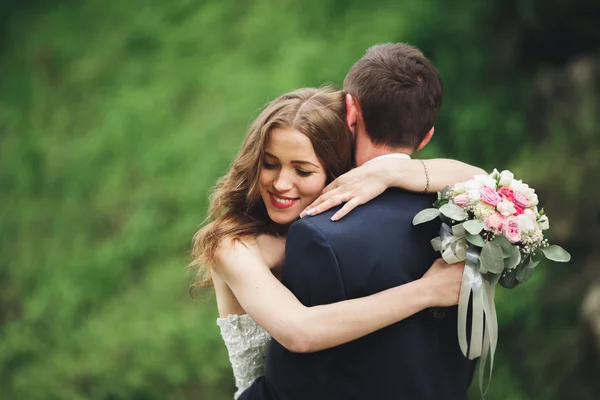 Счастливая свадебная пара обнимает и улыбается друг другу на фоне великолепных растений в замке — стоковое фото