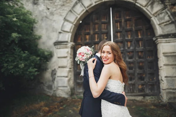 Joyeux couple de mariage étreignant et se souriant sur fond vieux château — Photo