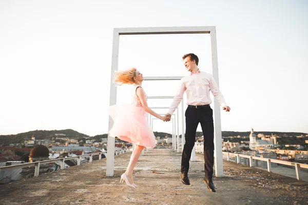 Amante casal pulando e sorrindo no telhado com fundo da cidade velha — Fotografia de Stock