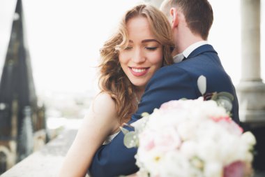 Güzel bir düğün çifti eski kasabanın arka plan panoramik manzarasında öpüşüp sarılıyor.