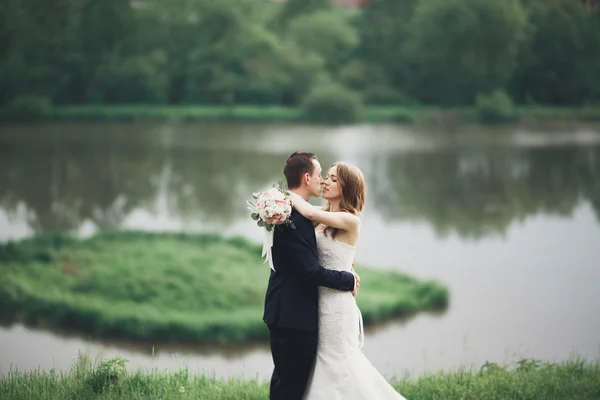 Όμορφο γαμήλιο ζεύγος φιλί και αγκαλιάζει κοντά στη λίμνη με το νησί — Φωτογραφία Αρχείου