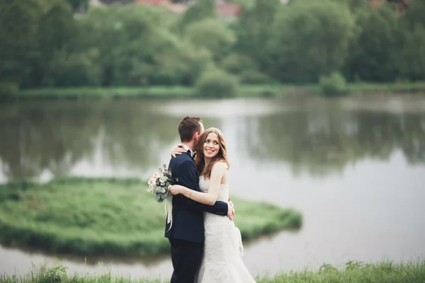 Casal de casamento lindo beijando e abraçando perto do lago com a ilha — Fotografia de Stock