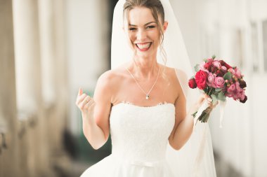 Lüks bir gelin, bir kız buketle poz veriyor ve gülümsüyor.