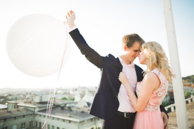 Çatıda mükemmel şehir manzaralı elele ve sarılma poz aşık genç bir çift. Güzel gün batımı