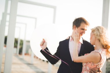 Çatıda mükemmel şehir manzaralı elele ve sarılma poz aşık genç bir çift. Güzel gün batımı