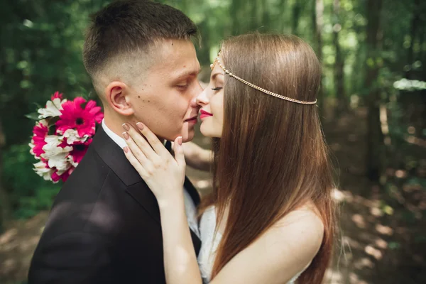 Красивая молодая свадебная пара целуется и улыбается в парке — стоковое фото