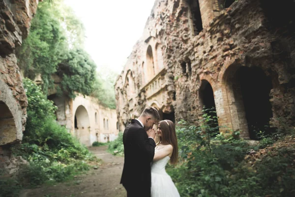 Gerade verheiratet posiert und küsst mit einer alten Festung im Hintergrund — Stockfoto