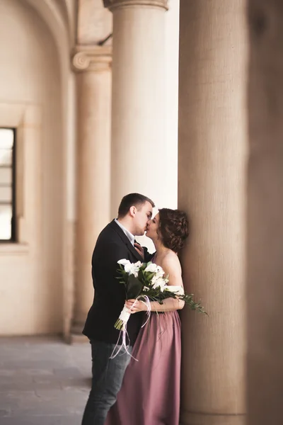 Glückliches Hochzeitspaar, Bräutigam, Braut mit rosa Kleid, einander umarmend und lächelnd auf den Hintergrundwänden im Schloss — Stockfoto