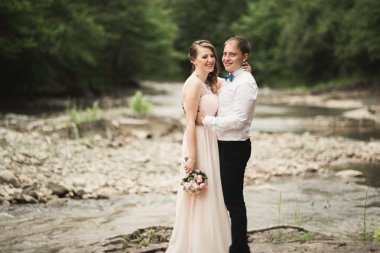 Zarif nazik şık damat ve gelin taşlarla Nehri yakınında. Evlilik çift aşık