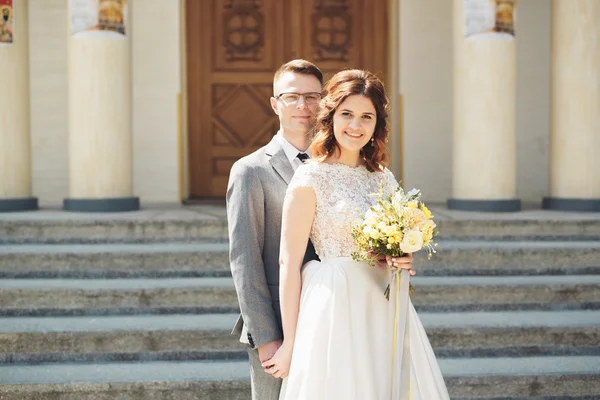 Menyasszony és a vőlegény, a háttérben a gyönyörű templom. régi épület. Arch. esküvő — Stock Fotó