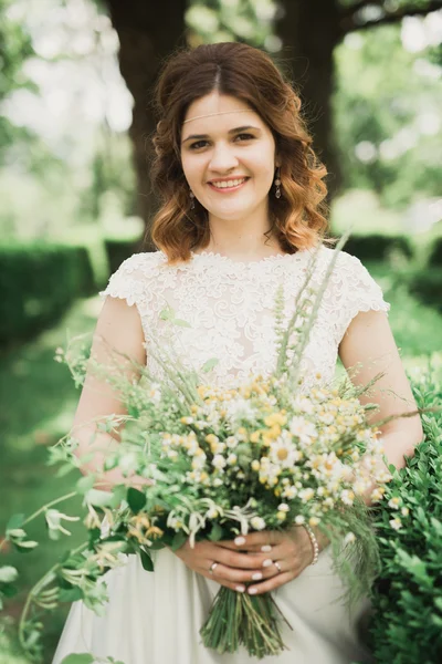 La novia sosteniendo ramo de flores en el parque. Boda — Foto de Stock