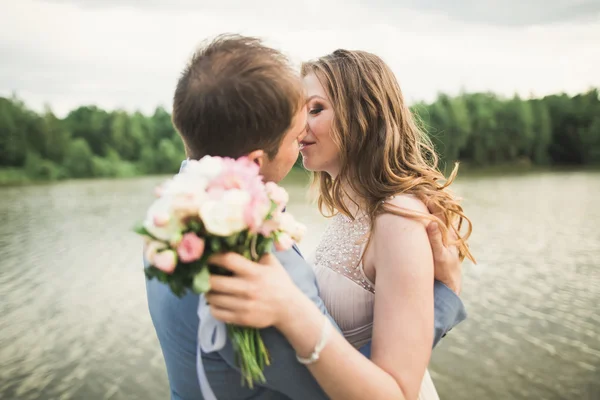 Счастливой свадьбы пара обнимает и улыбается друг другу на заднем плане озера, леса — стоковое фото