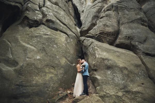 Glückliches Hochzeitspaar küsst und umarmt sich in der Nähe einer hohen Klippe — Stockfoto