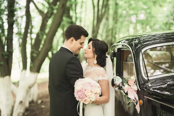 Gyönyörű friss házaspár pózol közel retro fekete autó — Stock Fotó