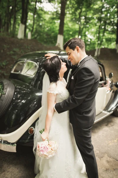 Felice coppia di sposi, uomo e moglie baciare vicino elegante auto retrò — Foto Stock