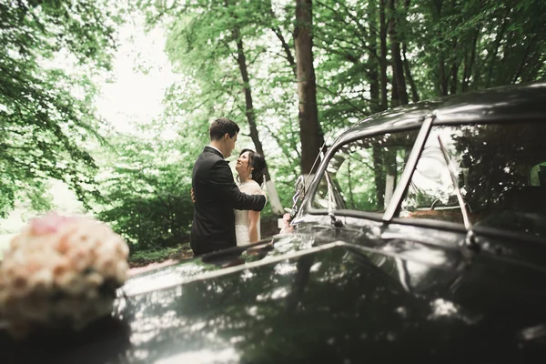 Bella coppia di sposi posa vicino retro auto nera — Foto Stock