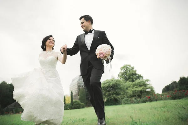 Frisch verheiratetes Paar rennt und springt im Park und hält Händchen — Stockfoto