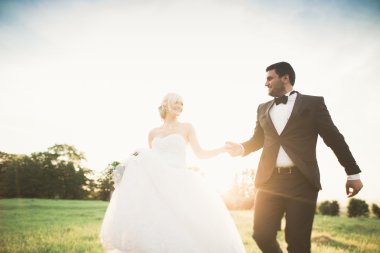 Yeni evli çiftimiz düğün günlerinde ellerinde buketle parkta yürüyorlar.