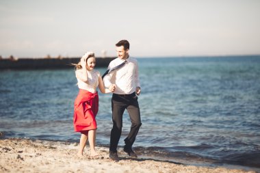 Genç mutlu çift holding birbirlerini etrafında gülümseyen Sahilde yürüyüş. Aşk hikayesi