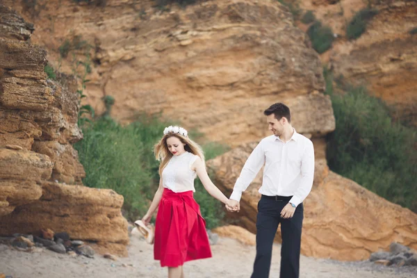 Romantica coppia amorevole a piedi sulla spiaggia con rocce e pietre — Foto Stock