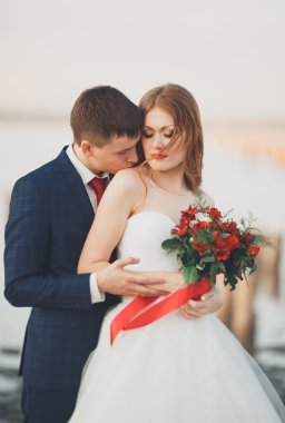 Güzel genç düğün çift, gelin ve damat arka plan denizde ahşap direklerin yakın poz