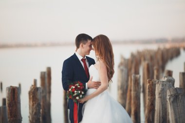 Çift düğün, damat, gelin buketi günbatımı üzerinde denize yakın poz ile