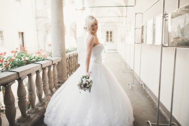 Lüks bir gelin, bir kız buketle poz veriyor ve gülümsüyor.