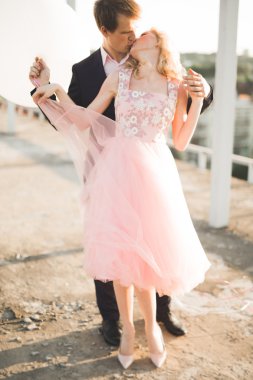 Çatıda mükemmel şehir manzaralı elele ve sarılma poz aşık genç bir çift. Güzel gün batımı