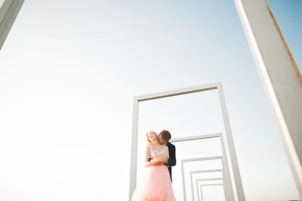 Jovem casal apaixonado posando no telhado com vista perfeita da cidade de mãos dadas e abraços. Belo pôr do sol — Fotografia de Stock