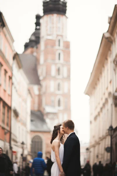 Hermosa pareja de boda, novia, novio besándose y abrazándose de pie en la multitud —  Fotos de Stock