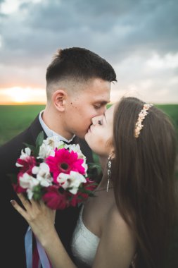 Düğün, güzel romantik gelin ve damat öpüşme günbatımında kucaklayan