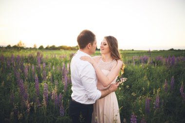 Gelin ve damat, çiçekler, güzel bir alanda gün batımında rissing romantik evli çift