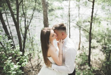 Düğün iki adam, öpüşme ve nehir, dağlar bir arka plan üzerinde sarılma gelin. Güzellik Portresi