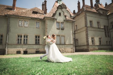 Güzel, romantik bir düğün. Yeni evliler. Eski kalenin yakınlarında sarılıyorlar.