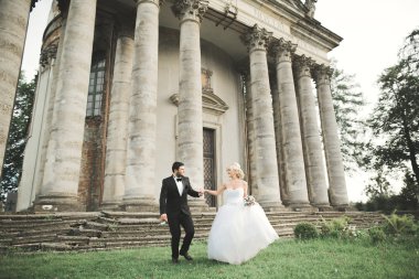 Güzel, romantik bir düğün. Yeni evliler. Eski kalenin yakınlarında sarılıyorlar.
