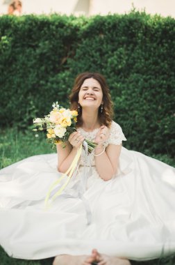 güzel gelin kameraya gülümseyen bir buket tutarak yere oturup...