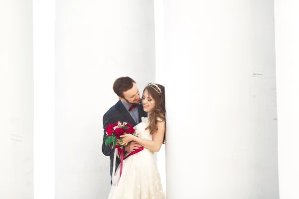 Hermosa pareja, novia y novio posando cerca de gran columna blanca — Foto de Stock