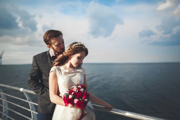 Casamento casal em pé em um cais sobre o mar — Fotografia de Stock