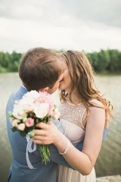 幸せな結婚式のカップルを抱き締めると背景湖、森林の互いに笑みを浮かべて — ストック写真