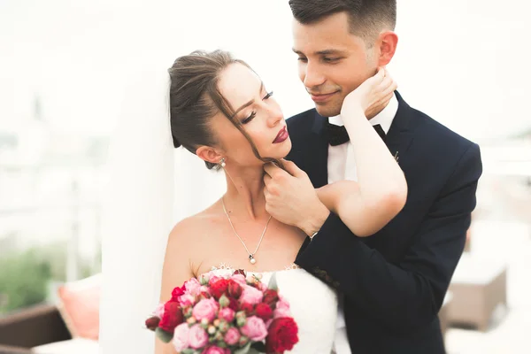 Beautiful couple, bride and groom posing on balcony with backgrounf of old city — Stock Photo, Image