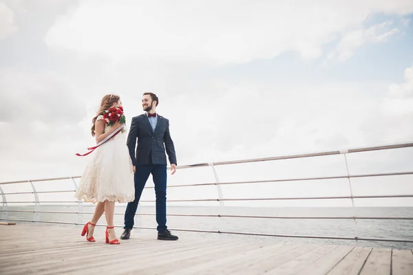 Casamento casal em pé em um cais sobre o mar — Fotografia de Stock