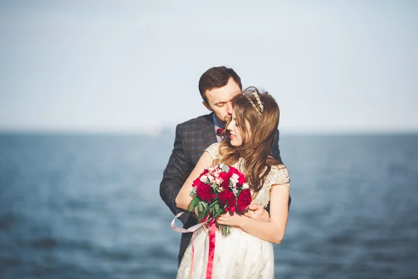 Pareja de recién casados caminando en la playa al atardecer . — Foto de Stock